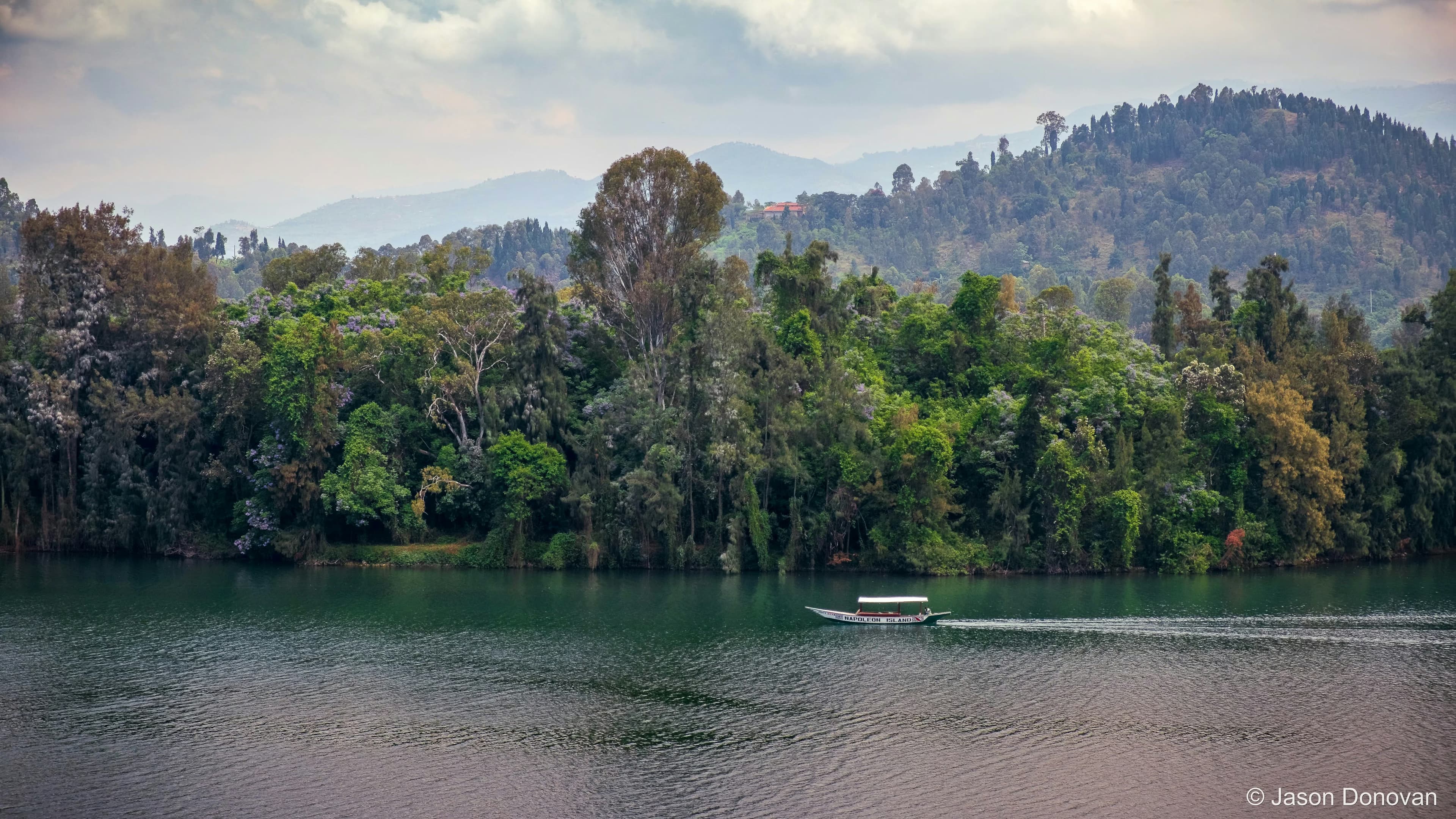 Toursit Boat with forest backdrop Rwanda photography by Jason Donovan