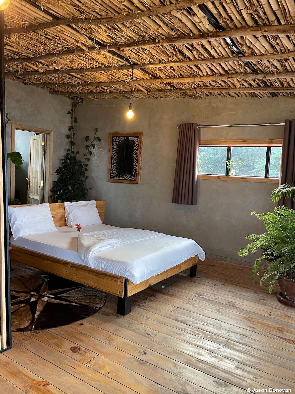 Rustic lodge bedroom with bamboo ceiling and wooden floor Rwanda