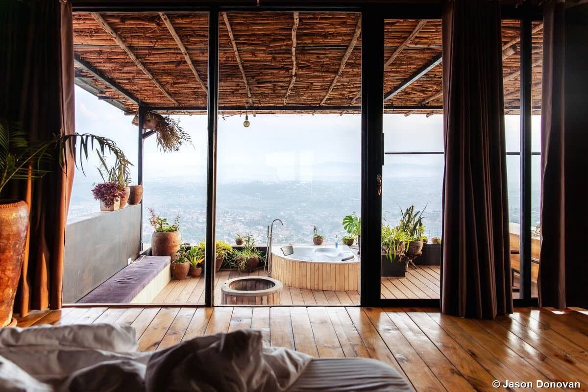 Lodge room view through glass doors to lake balcony Rwanda